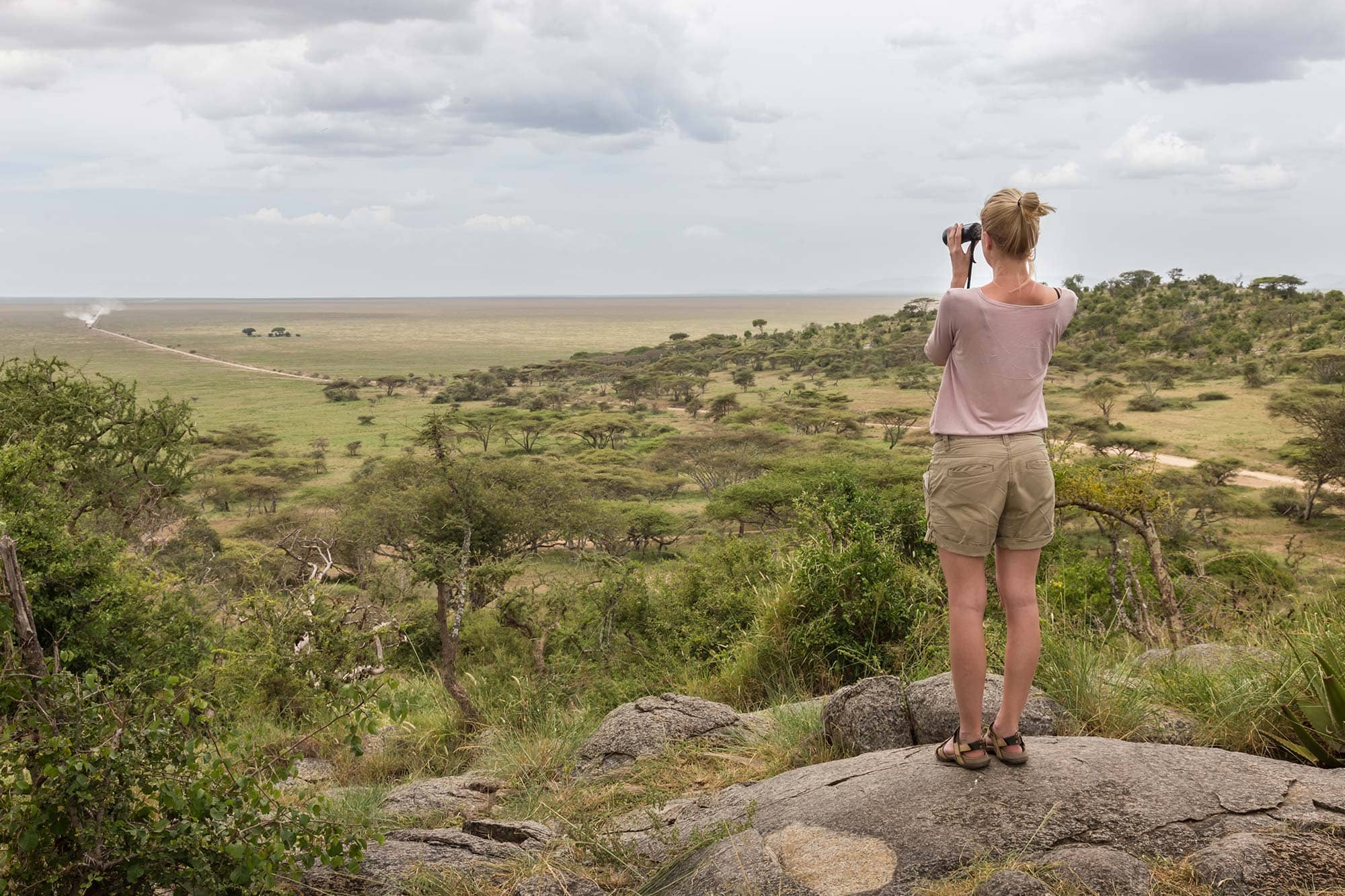 Woman taking photos in the Serengeti with appropriate safari attire