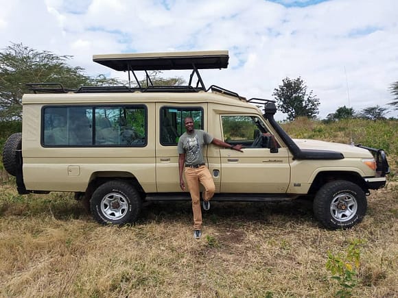 Seif Manyama stands next to a safari vehicle