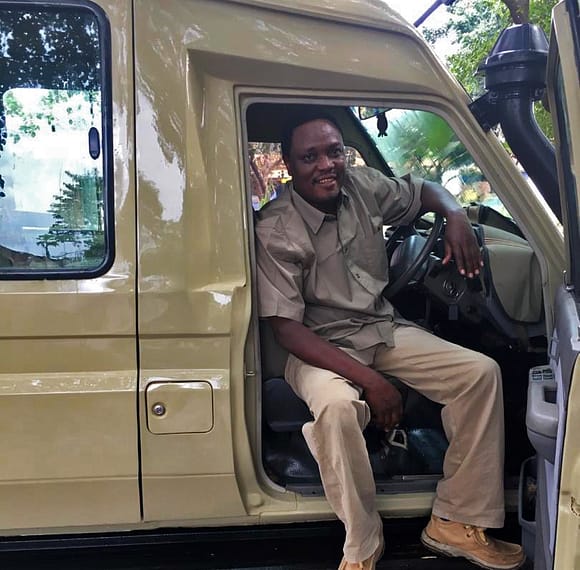 Boniface Lyimo sits in the passenger side of a safari vehicle