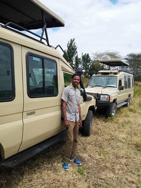 Mussa Rajabu standing next to his safari vehicle
